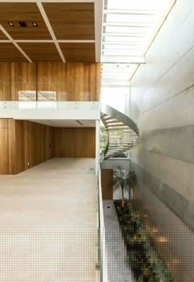 ma curva de um ambiente para o outro: escada dessa casa é posicionada para o corredor aberto com jardim de inverno