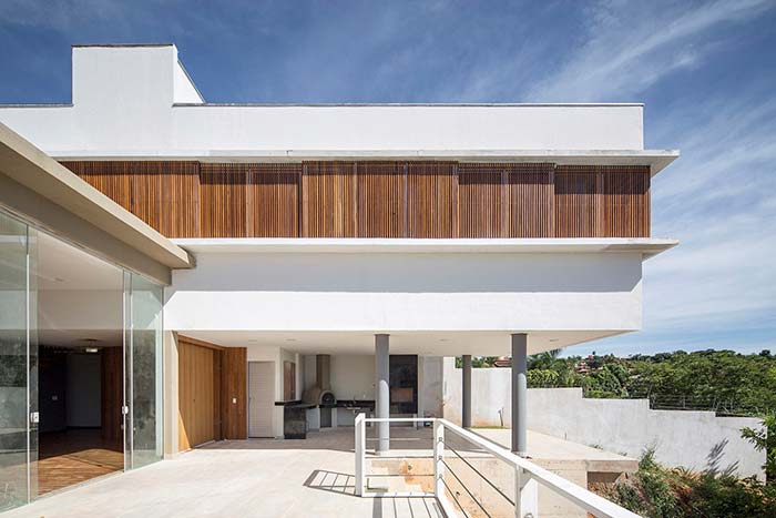 Casa branca, detalhes em madeira e telhado embutido