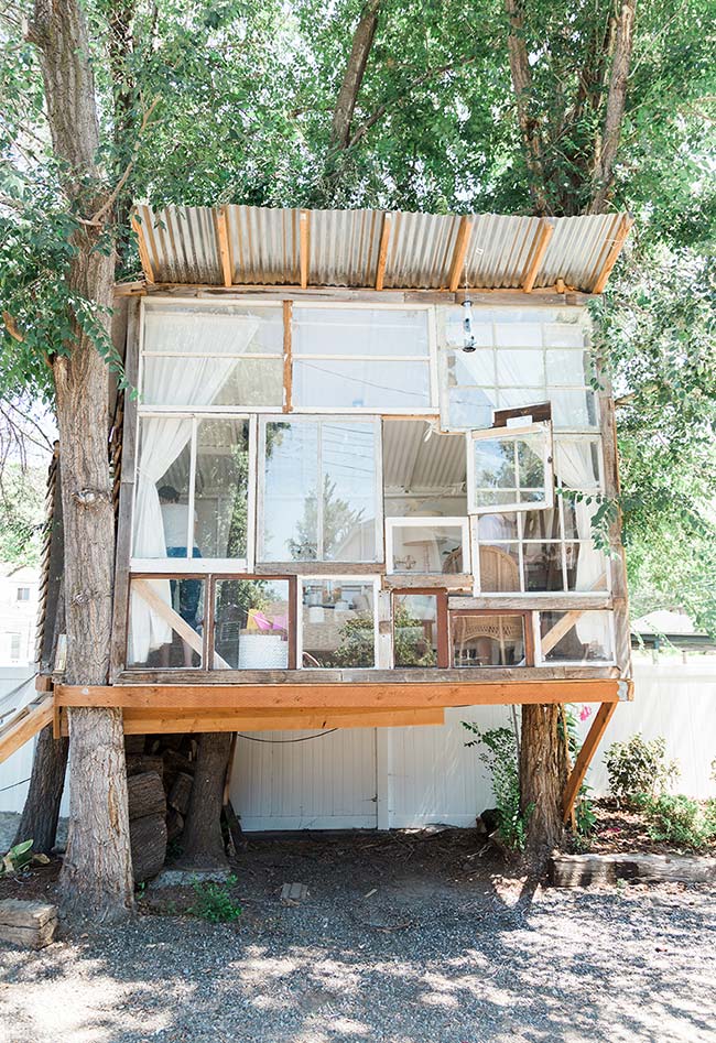 Também no estilo rústico, esta casa na árvore em madeira usa janelas de vidro para fazer uma parede livre para a iluminação do sol