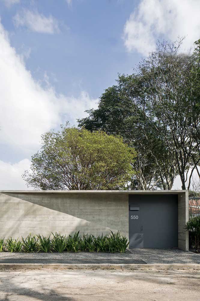 Muro com revestimento de pedra compartilha espaço com o portão fechado de aço