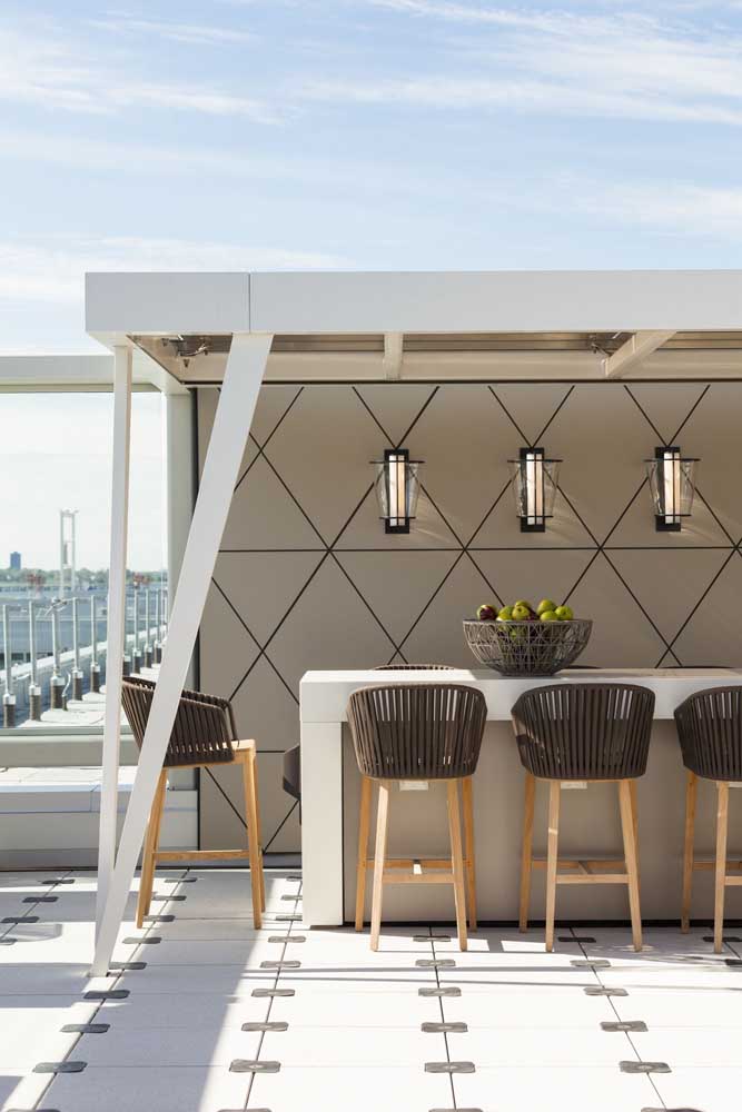 A cobertura sobre a mesa garante um refúgio do sol e da chuva; repare que a altura maior das cadeiras garante um clima despojado para a área gourmet