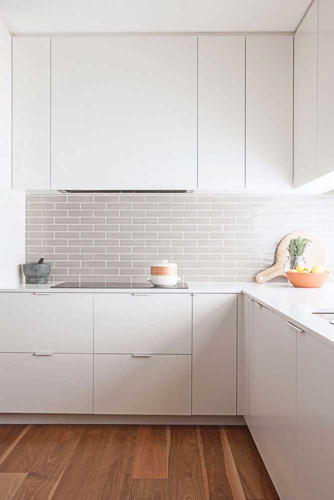 Com design minimalista, essa cozinha planejada de canto aproveita o espaço com armários maiores