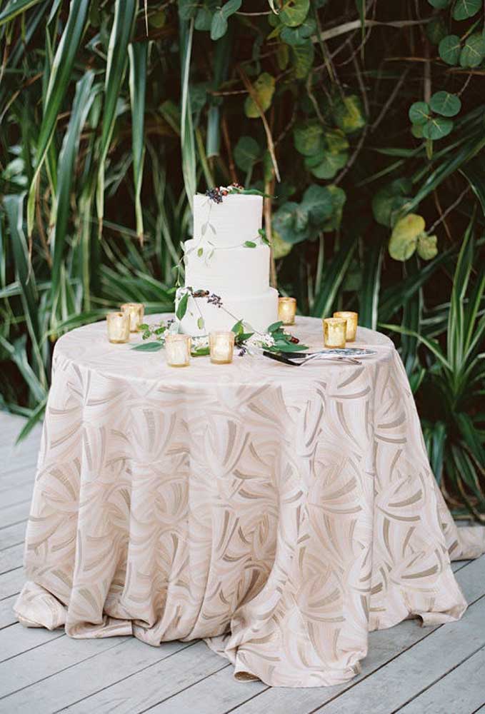 Um bolo simples e barato para casamento pode ser feito usando pasta americana e não precisa fazer muitos andares. Decore a mesa com velas e uma linda toalha.