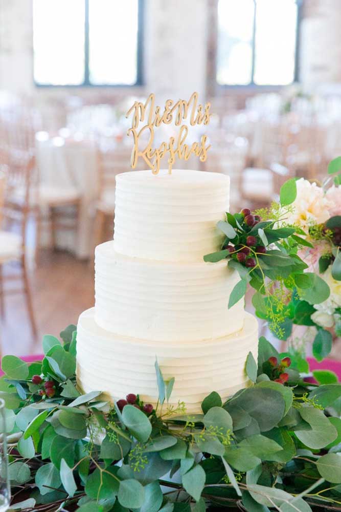 Folhas e flores artificiais são perfeitas na hora de decorar a mesa do bolo de casamento.