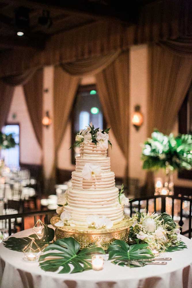 Uma boa decoração para a mesa do bolo de casamento é usar algumas folhas grandes e acrescentar algumas velas ao redor. Mas capriche na base onde será colocado o bolo.