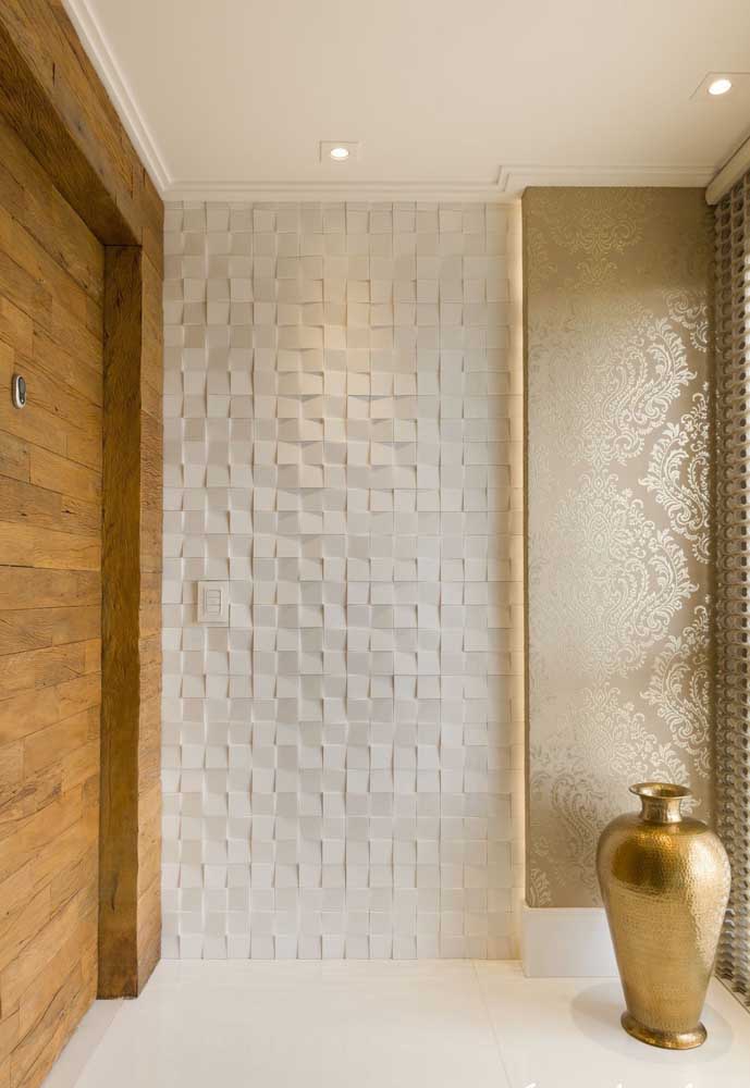 No hall de entrada, o revestimento branco abre espaço para que os detalhes em dourado se sobressaiam