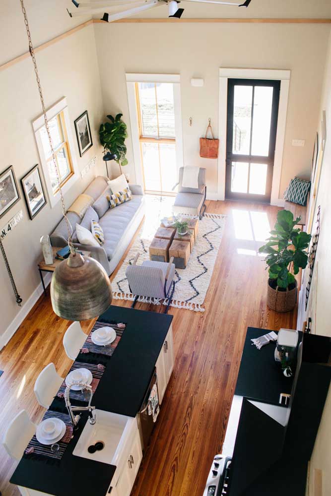 Um único ambiente dividido entre sala de estar, jantar, cozinha e hall de entrada, a solução foi criar diversas áreas livres de circulação 