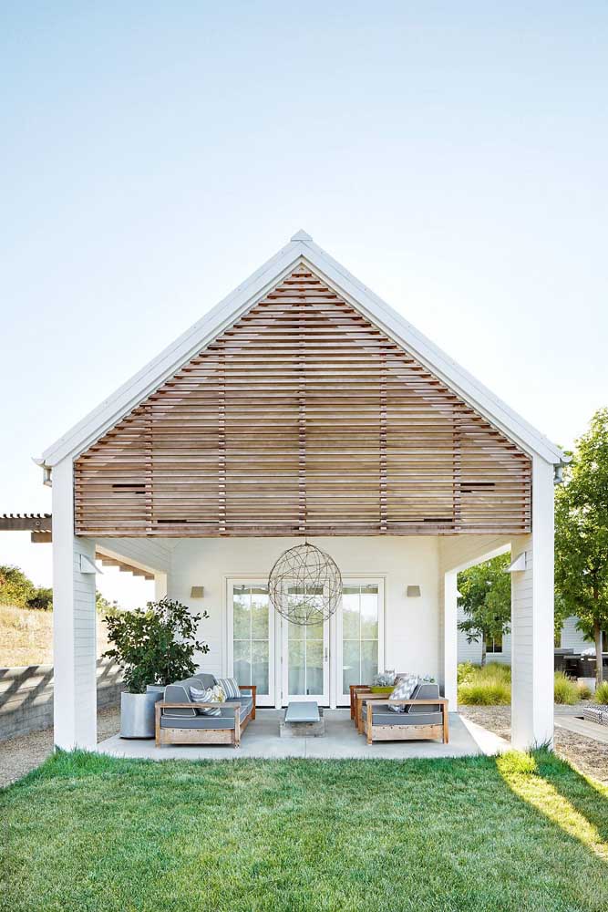 Essa pequena casa de pé direito alto traz uma fachada encantadora com ripas de madeira