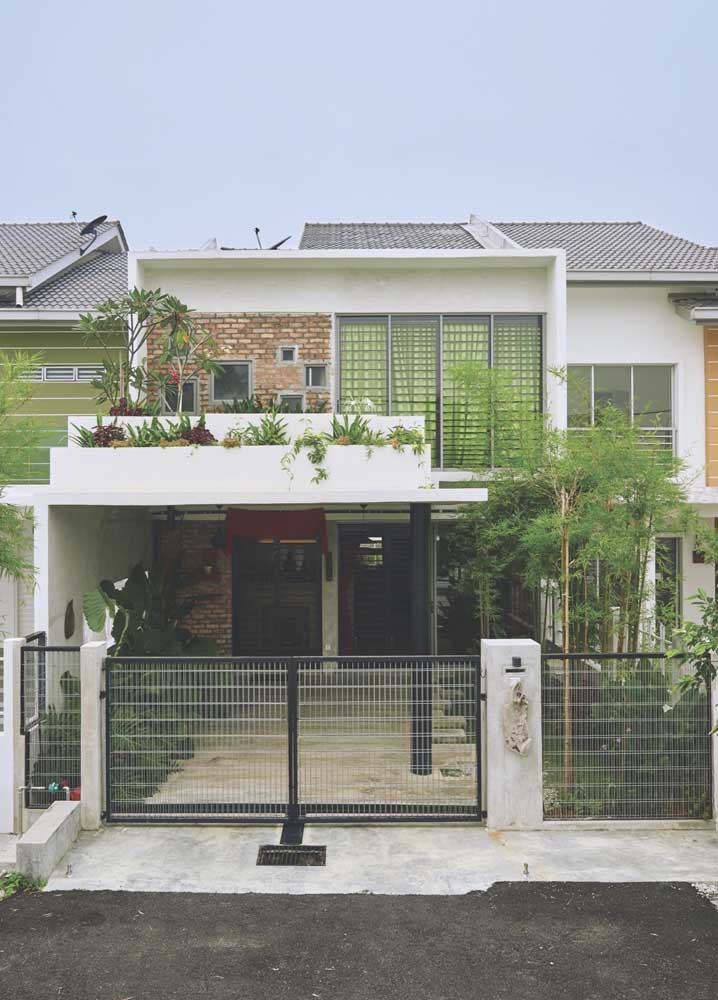 Uma casa simples destacada pelo jardim na entrada e pelo uso de tijolinhos aparentes na fachada