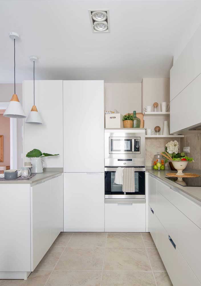 Cozinha americana simples e pequena com balcão; o branco amplia a sensação de espaço e traz um visual clean para o ambiente
