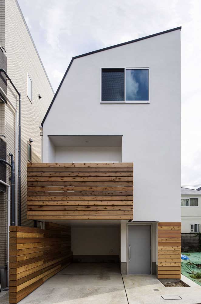 Fachada de casa pequena com varanda e garagem; o destaque aqui vai para o revestimento de madeira