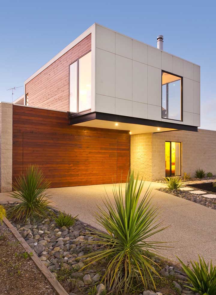 Já essa outra casa moderna, apostou em uma fachada com jardim de estilo rústico e desértico