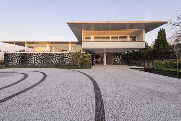 Fachada de casa moderna e imponente com destaque para o muro de revestimento preto e branco