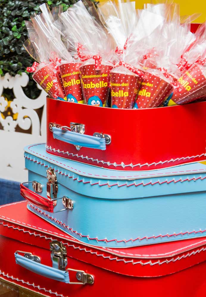 O que acha de organizar as lembrancinhas dentro de malas de viagem? 