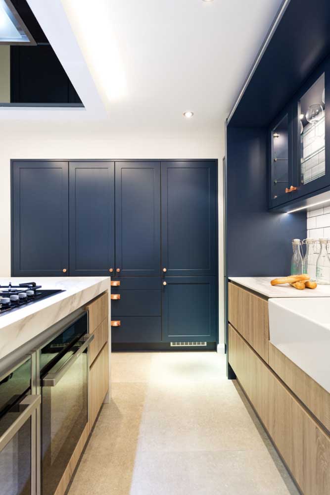 Na cozinha, o azul marinho pode se destacar em áreas maiores como os armários, nesse modelo, inclusive, a cor foi usada para criar uma faixa na parede sobre a pia