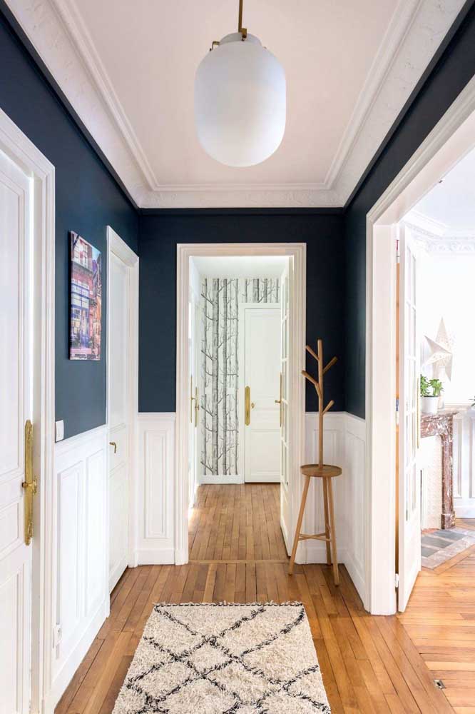 O corredor bem iluminado dessa casa apostou na pintura meio a meio usando branco e azul marinho