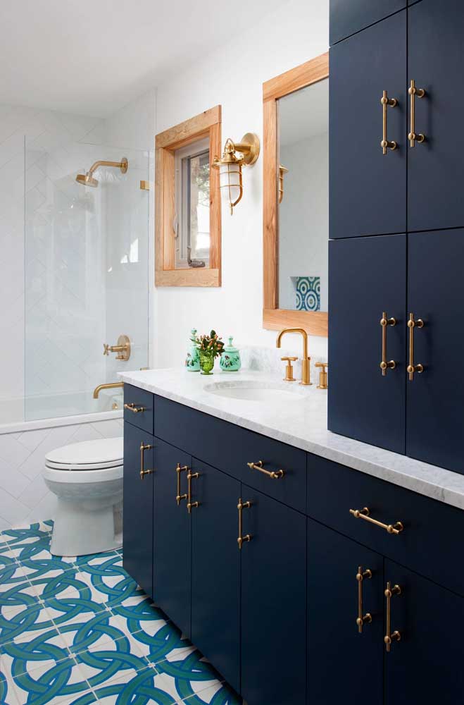 Nesse banheiro, o azul marinho também ganha espaço, mas divide a atenção com o piso em um tom mais claro de azul