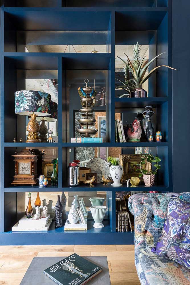 Nessa sala, a estante vazada azul marinho forma a divisória com os demais ambientes da casa