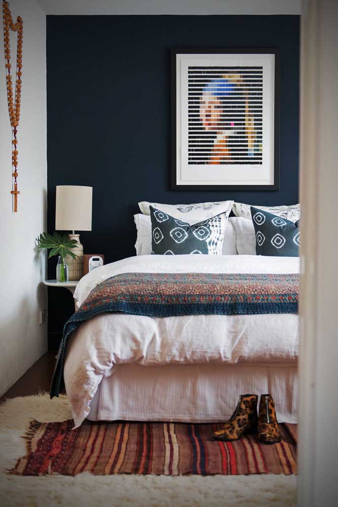 Nesse quarto de casal, o azul marinho se encontra na parede e na roupa de cama