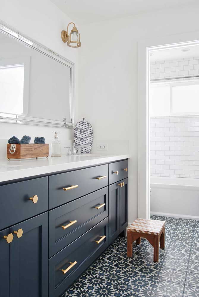 Linda inspiração de banheiro com ladrilhos hidráulicos azul marinho e branco; a cor se repete no armário com puxadores dourados