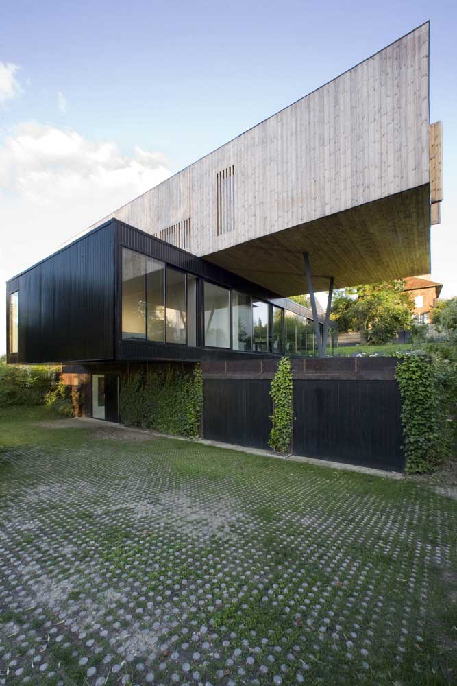 Casa moderna em L com grandes janelas; destaque para o conceito contemporâneo da obra