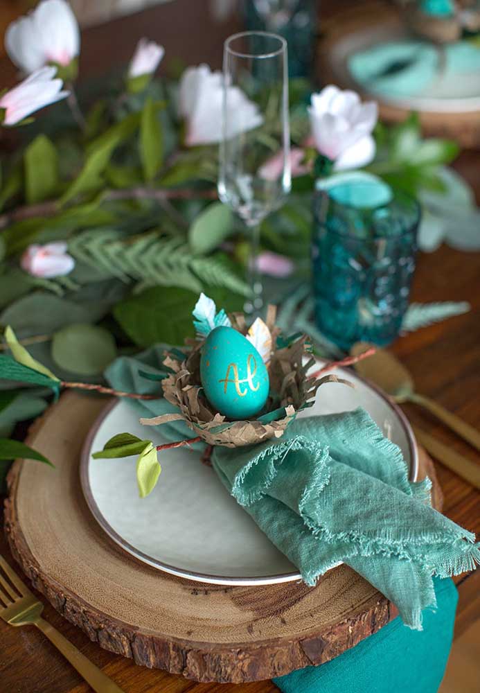 Quer apostar em uma decoração mais rústica para a Páscoa? Use um pedaço de madeira como jogo americano e decore o prato com um ovo pintado dentro de um cesto.