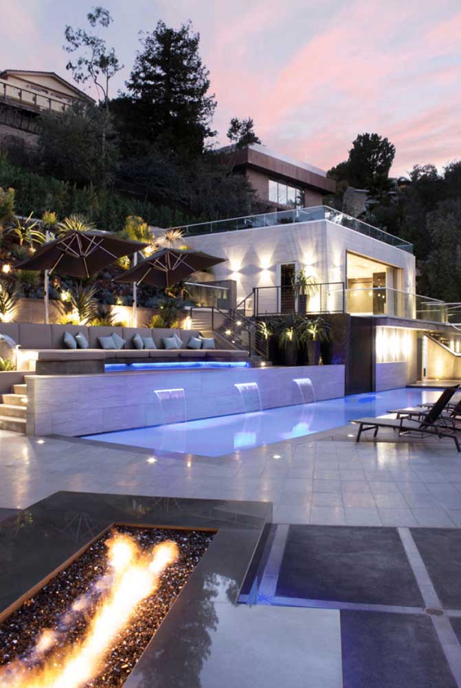 Edícula com escada para acesso à piscina; a iluminação completa o visual externo do espaço