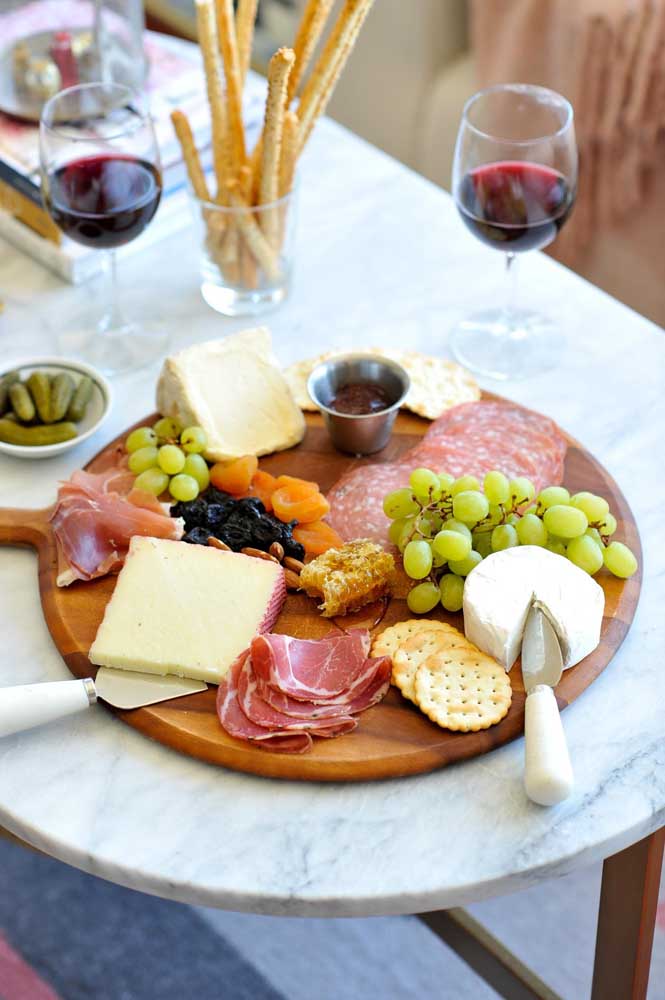 Mesa de frios simples e elegante, com embutidos, bolachas, frutas secas e vinho