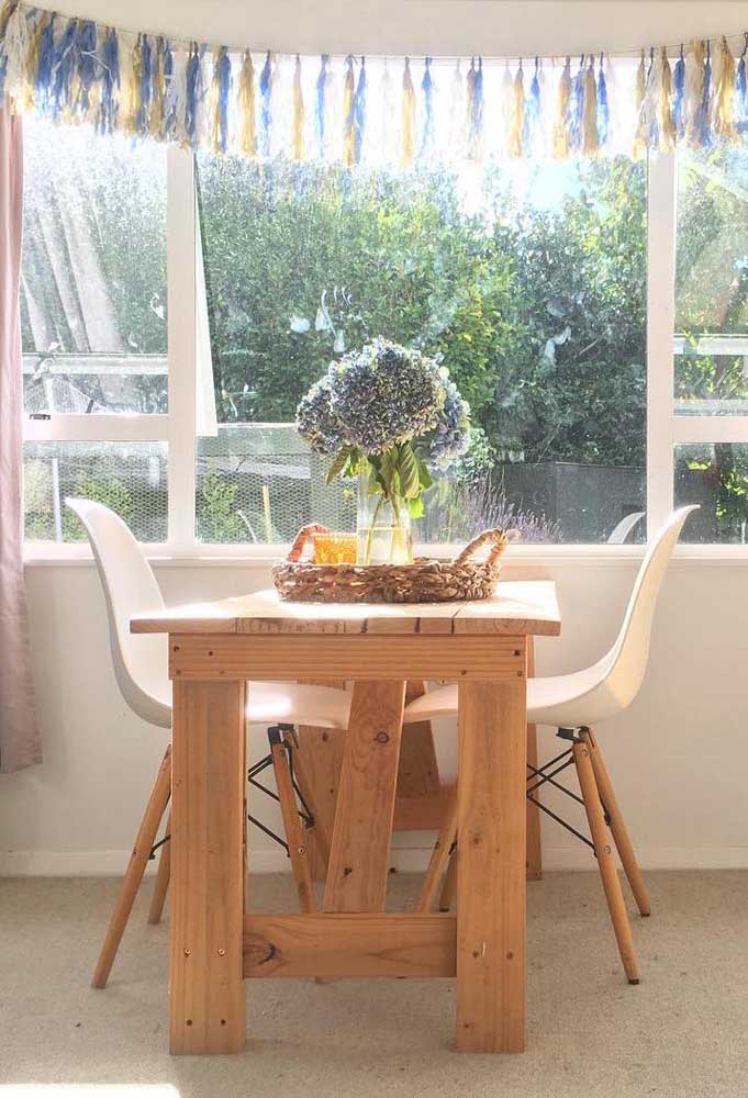 Mesa de pallet pequena para a sala de jantar acompanhada de cadeiras Eames, tendência do momento