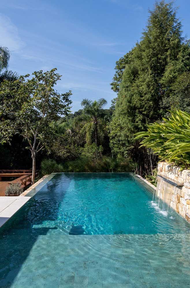 Um modelo de piscina com borda infinita em terreno plano que aproveita a cascata para dar movimento à água que escorre na borda