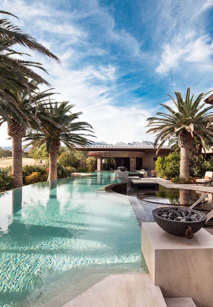 O design tropical da área externa dessa casa combinou super bem com a piscina de borda infinita