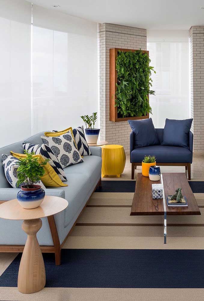 Varanda decorada com sofá azul claro e poltrona em azul petróleo; o amarelo, cor complementar ao azul, entra na decor para criar contraste