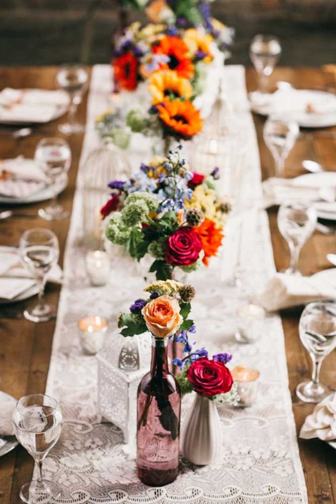 Essa mesa de casamento foi decorada com vasos altos cheios de flores coloridas