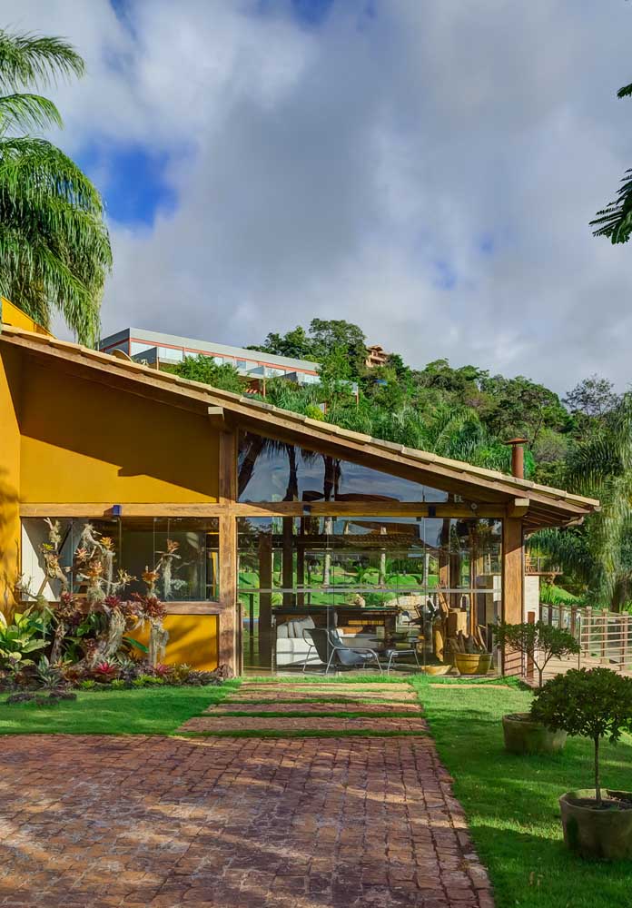 Casa térrea com telhado colonial meia água para a direita do terreno e estrutura em madeira à vista