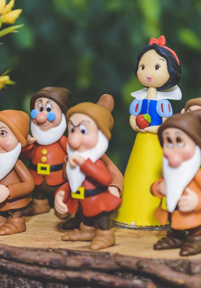 Os bonecos dos principais personagens do conto de fadas não podem faltar na decoração do centro de mesa Branca de Neve.