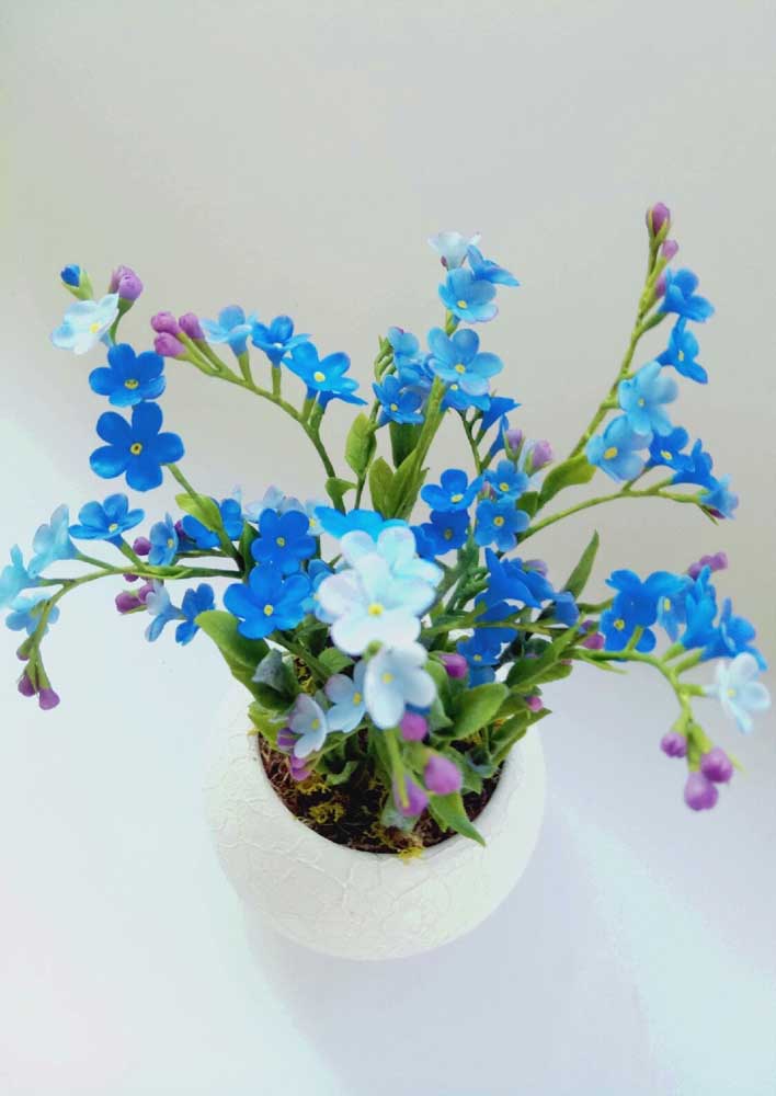 Flores pequenas e azuis dão graça a esse arranjo que leva musgo dentro do vaso, uma opção que também o torna mais real