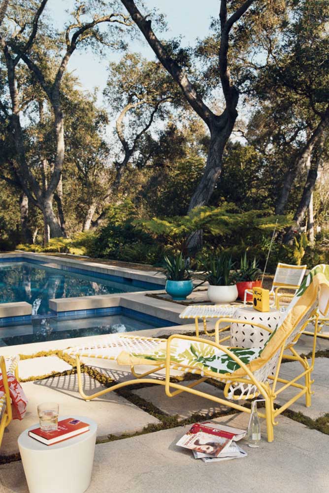 Área de lazer com piscina rodeada de árvores. As espreguiçadeiras deixam o lugar ainda mais convidativo