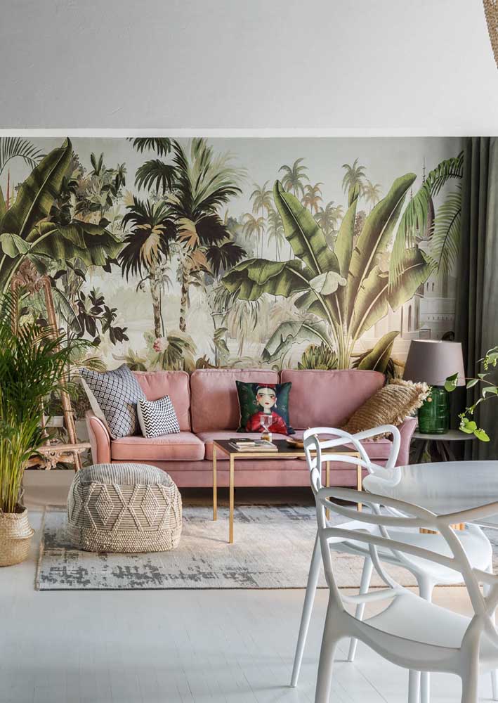 Sofá rosa chá na sala de estar com inspiração tropical. Repare como a composição entre rosa e verde é harmônica e equilibrada