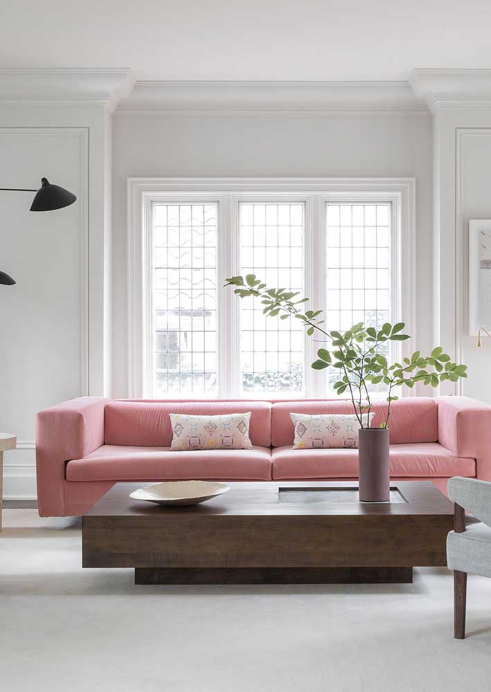 Aqui, a decoração de base clara e neutra ajuda a destacar o sofá rosa. Repare que ele também é o único elemento com cor na decoração