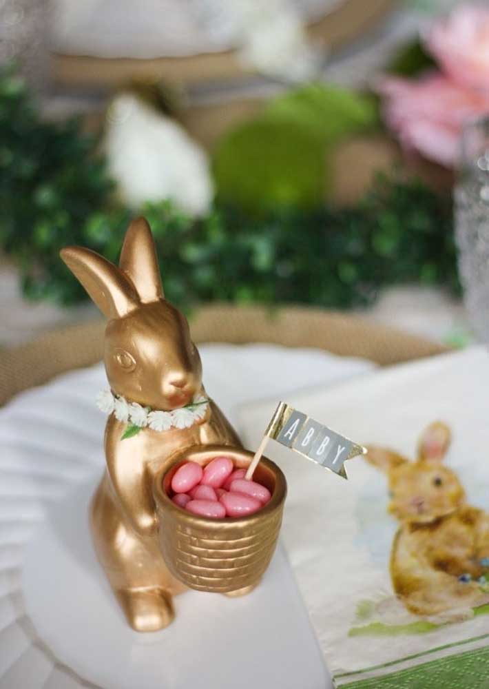 Coelhinha dourada trazendo os docinhos sobre a mesa de páscoa decorada