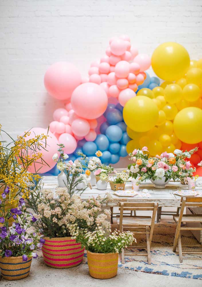 Decoração de festa descontraída com arranjos de flores do campo e balões coloridos