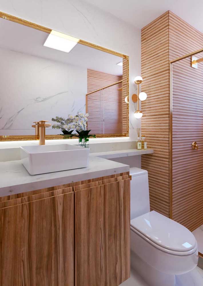 O dourado traz um toque de glamour ao banheiro amadeirado com branco