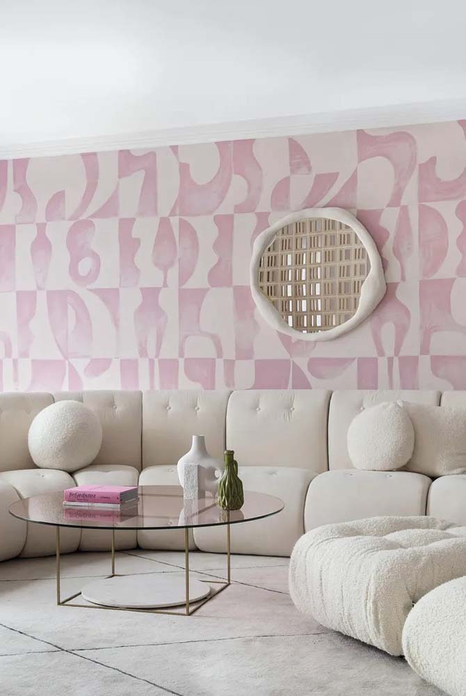 O fundo rosa do papel de parede forma um contraste delicado com o sofá