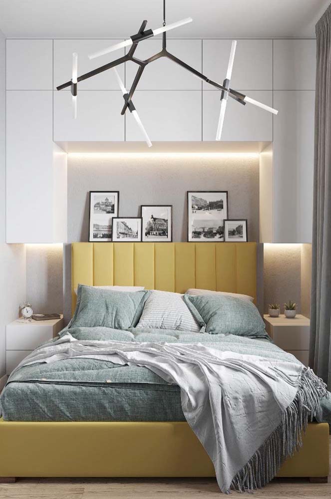 Uma cama amarelo pastel em contraste com os tons neutros do quarto
