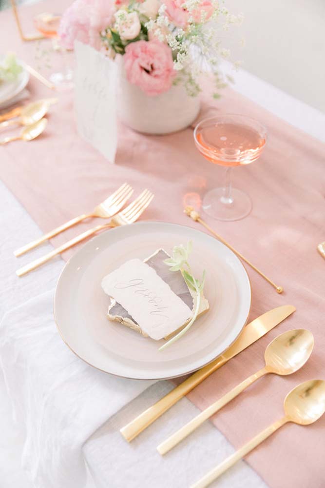 Composição delicada e sofisticada: uma faixa rosa no centro da mesa coberta por uma toalha de TNT branca.