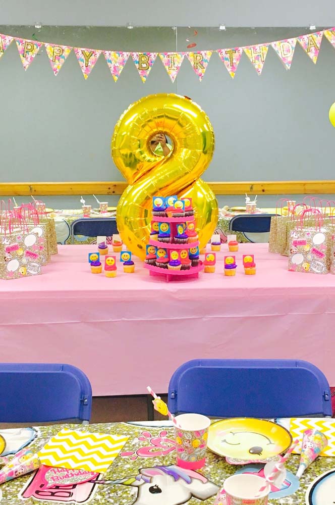 Mesa de cupcakes e lembrancinhas coberta com TNT rosa claro nesta festa de aniversário.