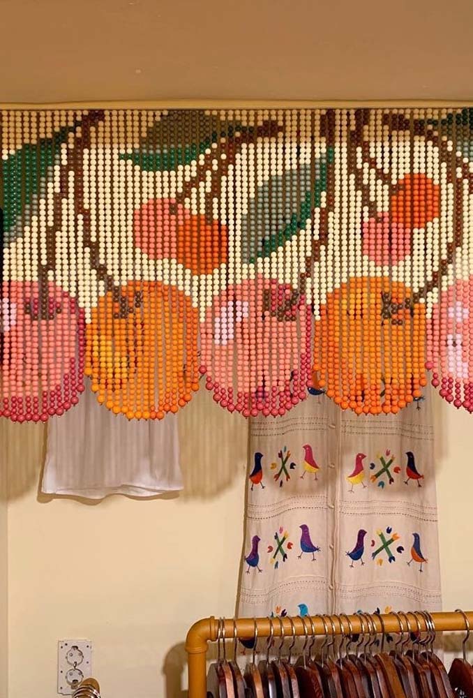 Apesar de curta, essa cortina de miçangas para cozinha com barra arredondada rouba a cena com o padrão de laranjas.