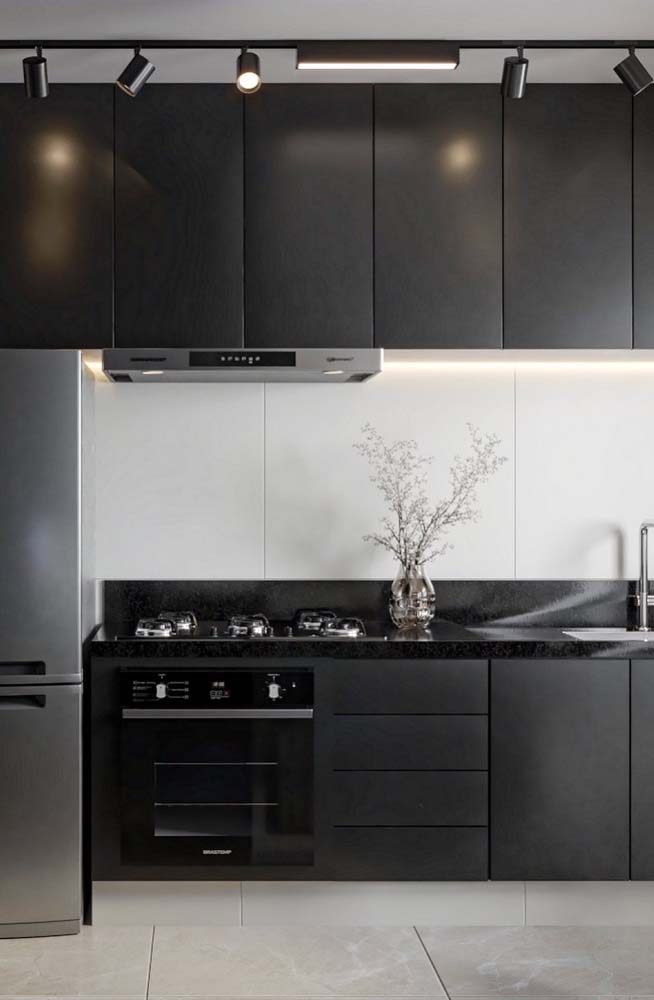 A iluminação valoriza o projeto da cozinha preta e branca