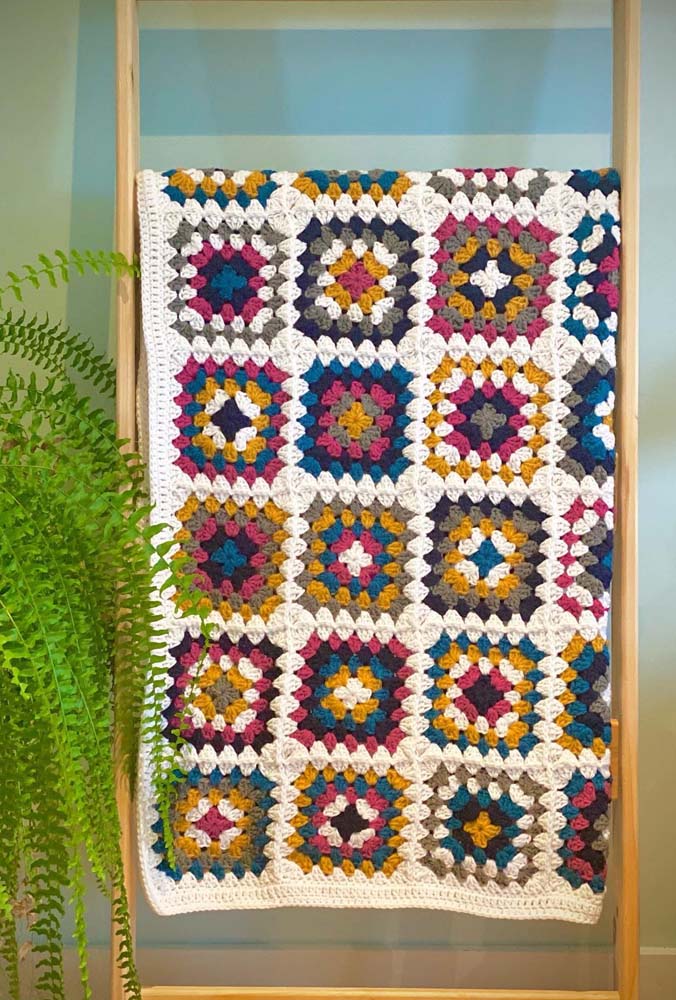 Tapete de crochê com square fácil que intercala cinco cores diferentes e fundo de barbante cru.