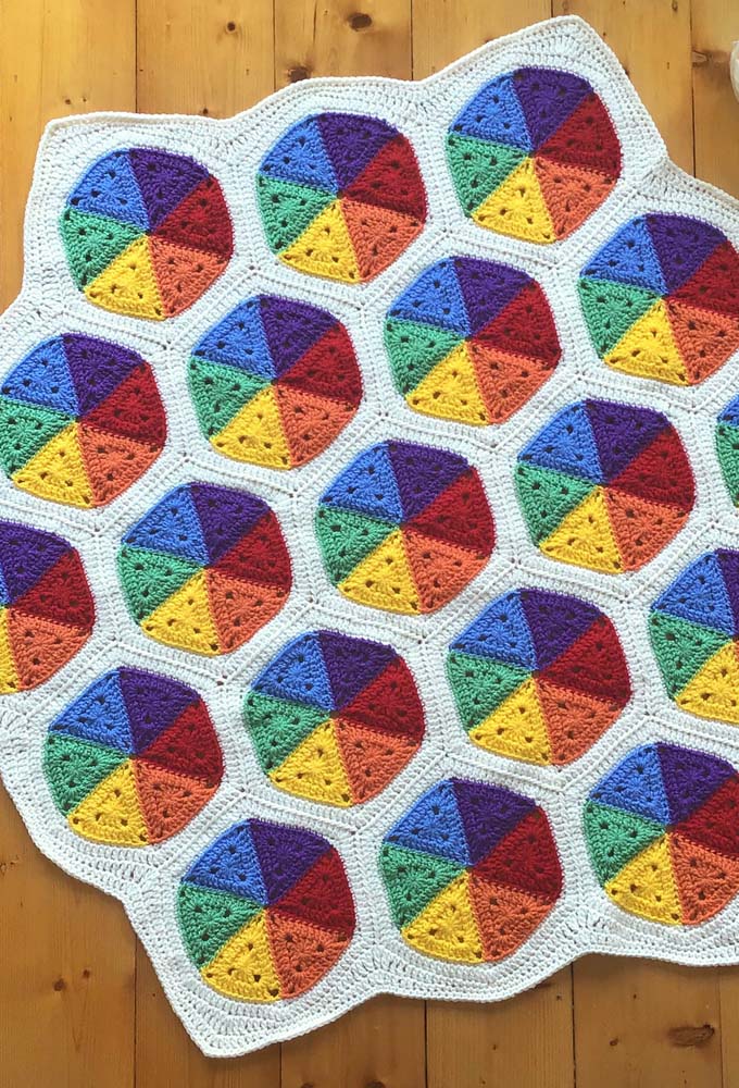 Seis triângulos coloridos com as cores primárias e secundárias formam os hexágonos desse tapete de crochê com square pequeno. 